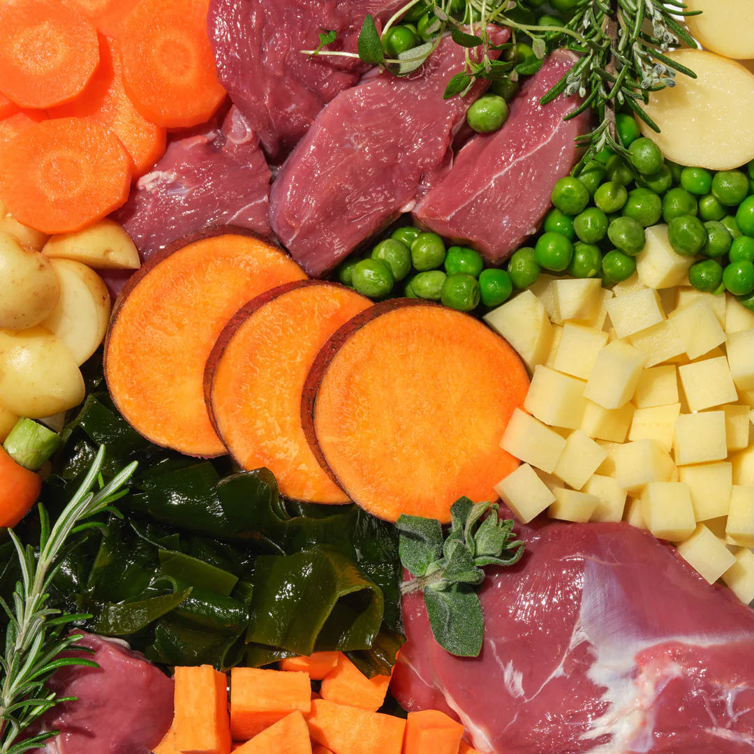 Assorted raw ingredients including sliced carrots, duck, peas, potatoes and seaweed.