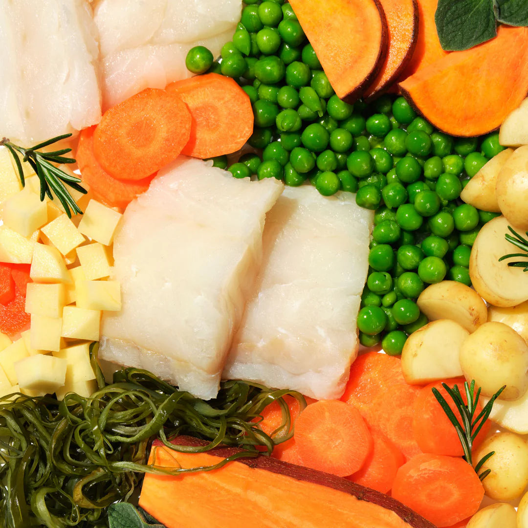 Raw fish fillets with sliced carrots, green peas, seaweed and potatoes.
